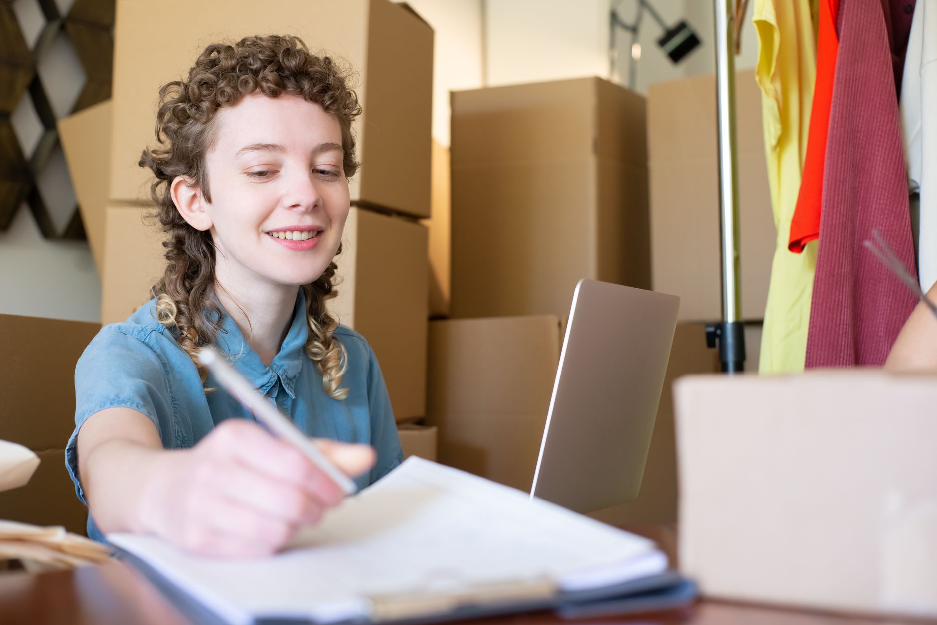 D2C brand owner managing ecommerce orders with laptop and shipping packages from home