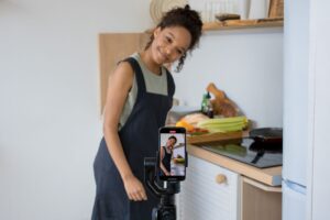 Young woman creating UGC content for D2C brand on smartphone in kitchen
