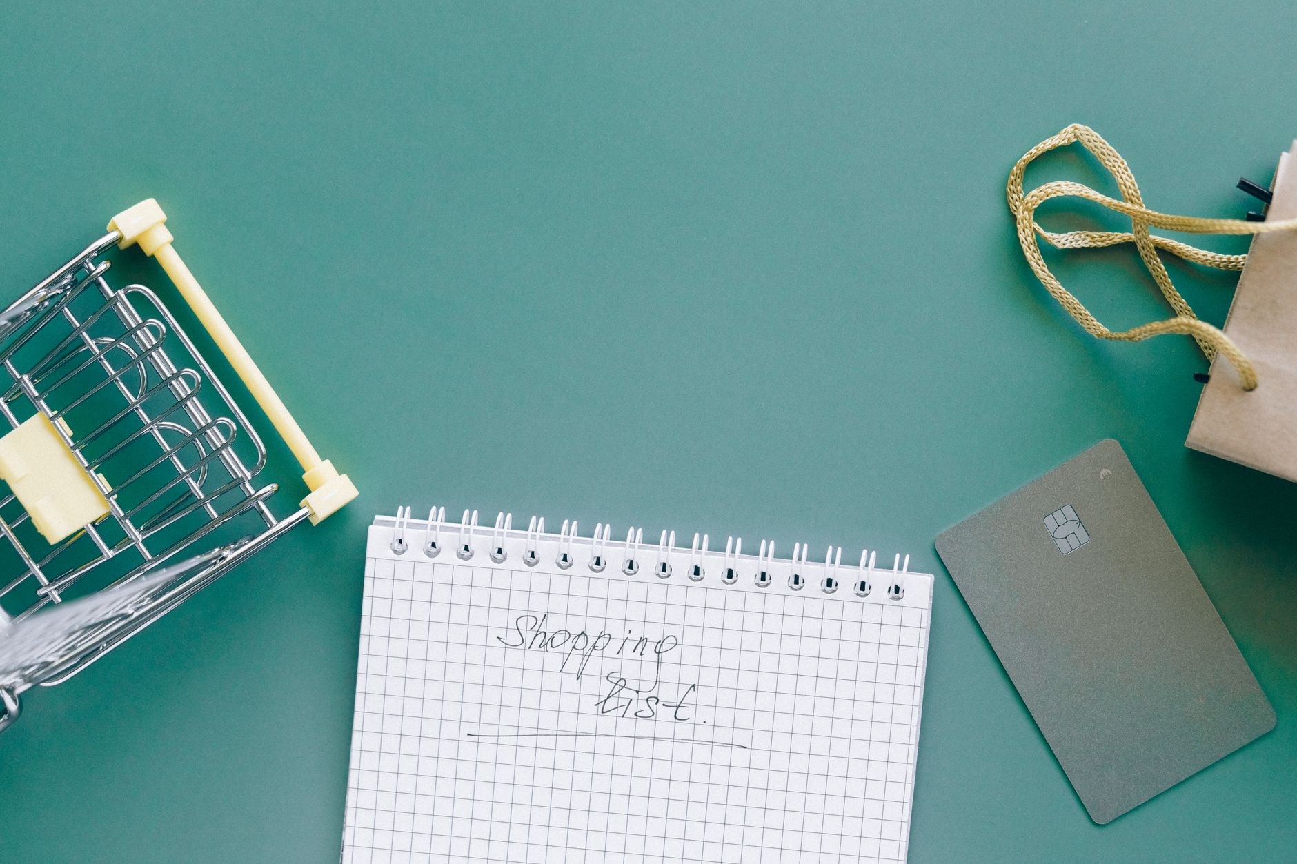A top-down view of a shopping cart, list, card, and bag on a green background representing ecommerce strategy for D2C brands