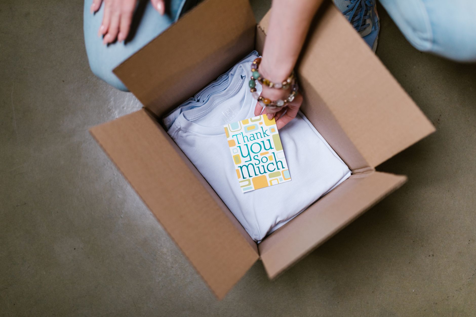 Person packing a subscription box with a thank you card — DTC ecommerce fulfillment experience