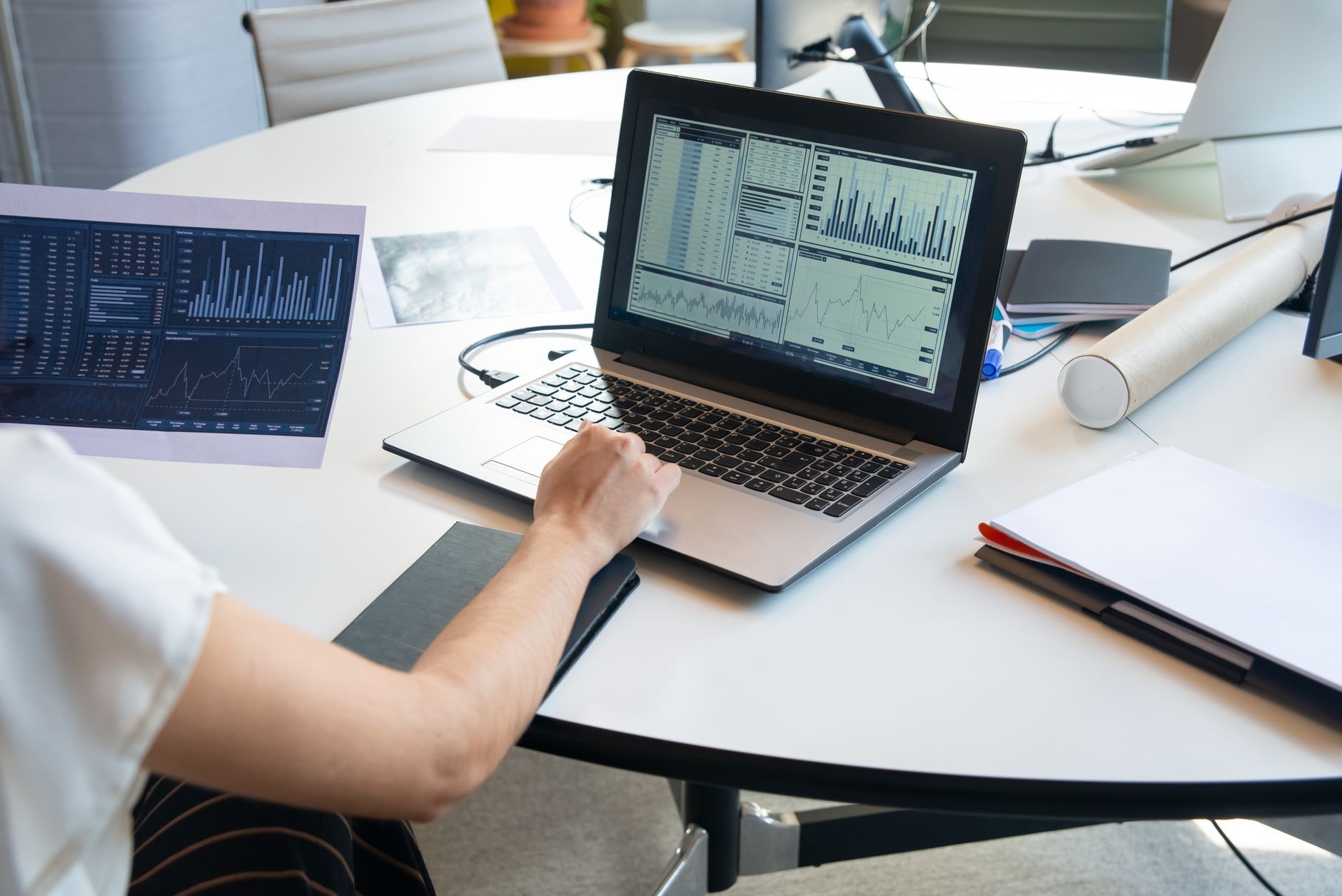 Business person evaluating financial charts on a laptop in a modern office setting