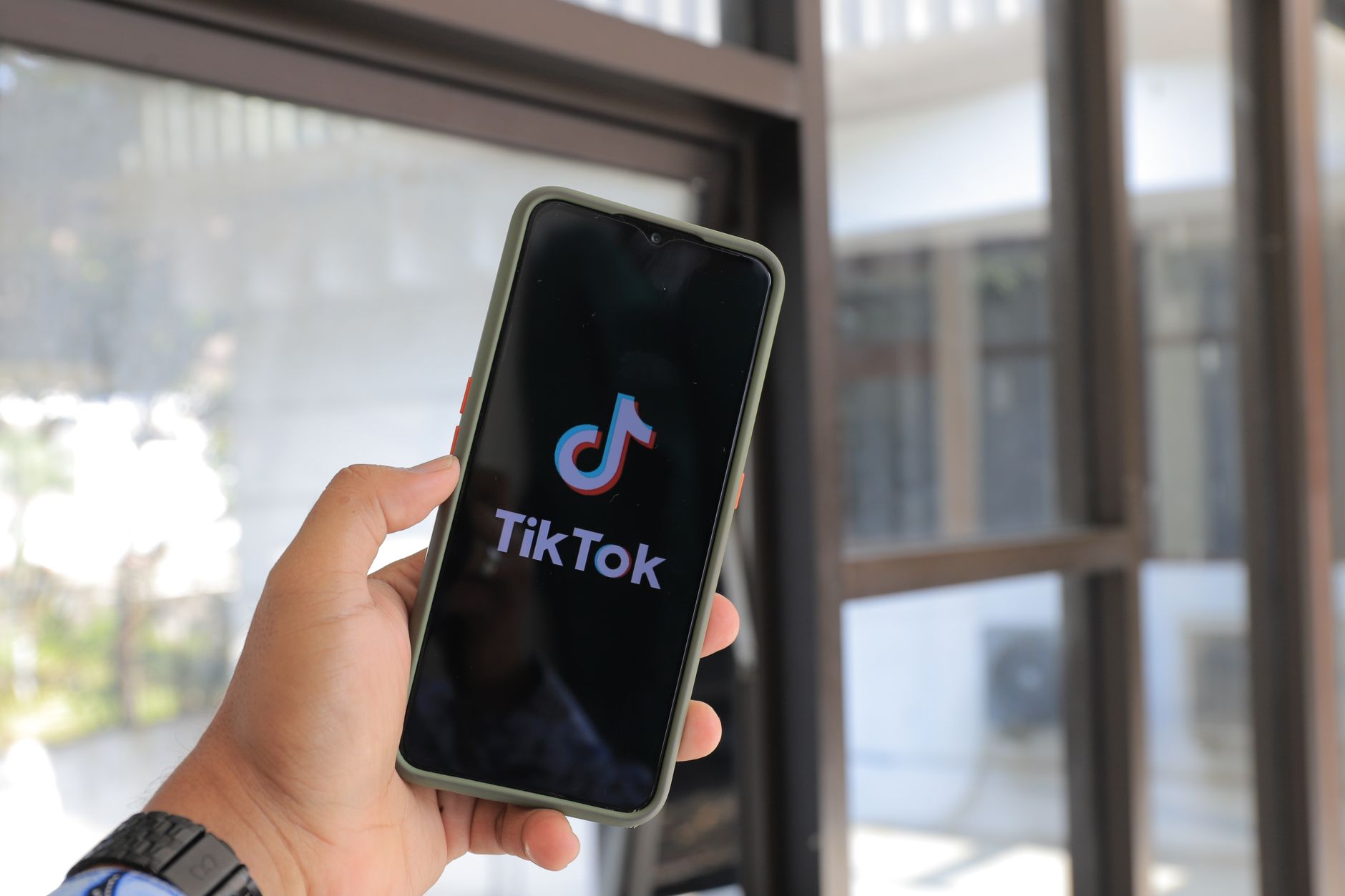 Hand holding smartphone displaying TikTok app — TikTok Ads for US DTC brands guide